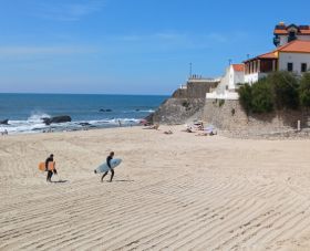 Two surfers carrying their surf board on the sand of Sao Pedro de Moel Beach in Portugal