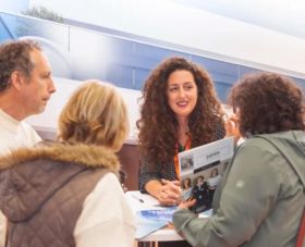 Denise Vieira certified realtor at an international property show talking with clients at Immo Portugal stand