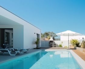 Outside pool desk and barbecue area of a modern villa sold by Immo Portugal