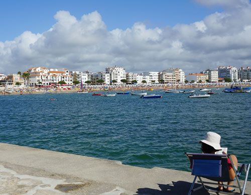 Woman sitting on a beach chair and reading on the pier of Sao Martinho do Porto - Portugal 
